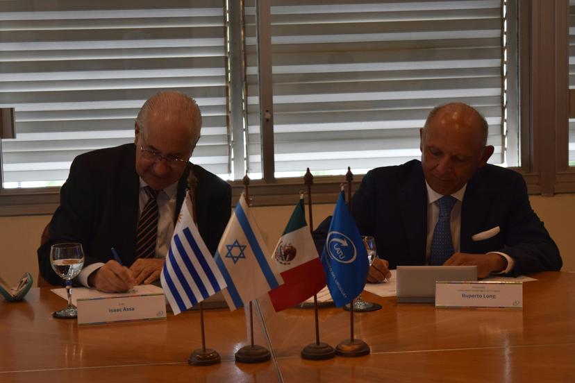 Ruperto Long e Isaac Assa Farca firman el convenio. Al frente: banderas de Uruguay, Israel, México y el LATU.